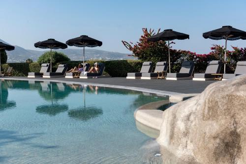 a pool with chairs and umbrellas and people sitting at Paros Agnanti Resort & Spa in Parikia