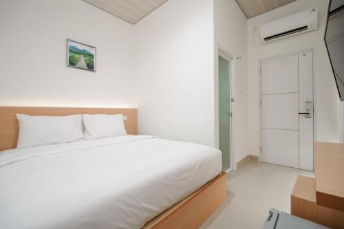 a white bedroom with a bed and a door at Urbanview keTemon Hotel & Resto YIA by RedDoorz in Yogyakarta
