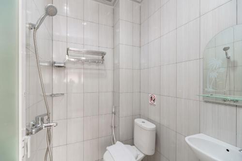 a white bathroom with a toilet and a sink at Urbanview keTemon Hotel & Resto YIA by RedDoorz in Yogyakarta
