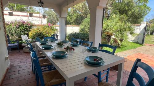 una mesa blanca con platos azules en el patio en Casa Bedda, en Agnone Bagni