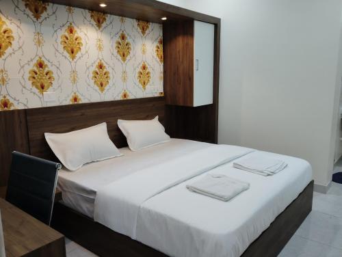 a bedroom with a large bed with white sheets at SR RESIDENCY in Chennai