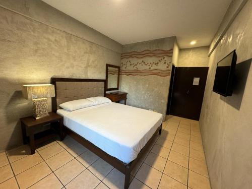 1 dormitorio con 1 cama y TV en Casa Patricia Hotel & Resort, en Candelaria