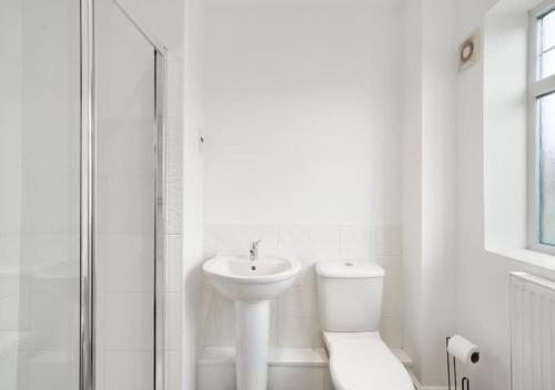 a white bathroom with a toilet and a sink at 4 Bedroom Apartment, near the airport & Free WiFi-Parking in Lincolnshire