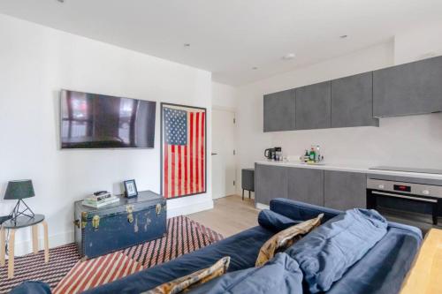 a living room with a blue couch and an american flag at Charming & Stylish 1BD Flat - Bethnal Green in London