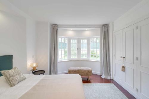 una camera da letto bianca con un letto e una finestra di Unique beach Villa with ocean view pool tennis a Cascais