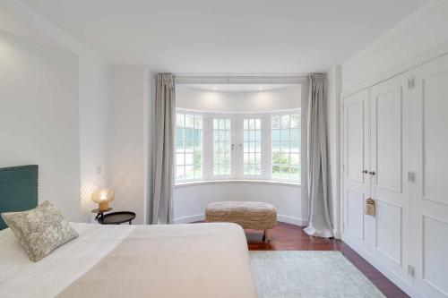 a white bedroom with a bed and a window at Unique beach Villa with ocean view pool tennis in Cascais