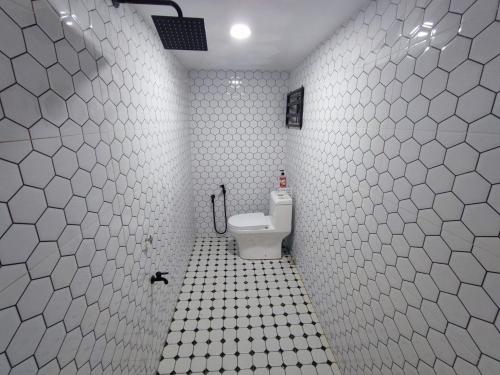 La salle de bains est pourvue de toilettes et d'un mur carrelé blanc. dans l'établissement Hermoso Homestay Kota Bharu, à Kota Bharu