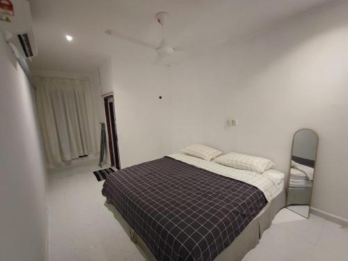ein Schlafzimmer mit einem Bett in einem weißen Zimmer in der Unterkunft Hermoso Homestay Kota Bharu in Kota Bharu