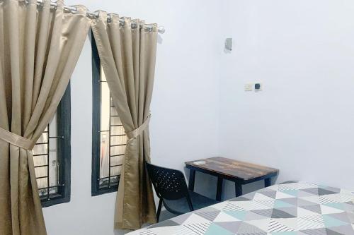 a bedroom with a table and a window with curtains at Pondokan Guest House Rinjani Syariah in Bengkulu