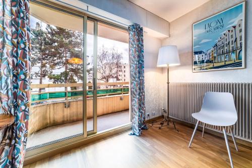 een kamer met een raam, een witte stoel en een tafel bij L'authentique d'Albertine proche Disneyland in Thorigny-sur-Marne