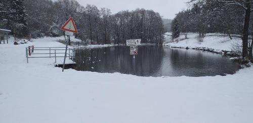 a river in the snow with a sign next to it at Alter Werkstatt in Jünkerath