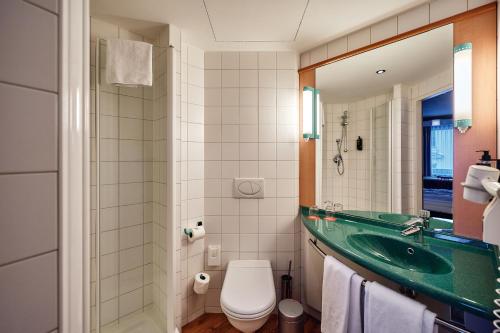 a bathroom with a green sink and a toilet at ibis Wien City in Vienna