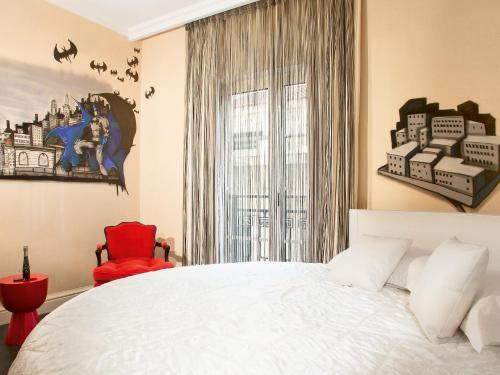 a bedroom with a large bed and a red chair at Grecotel Pallas Athena in Athens