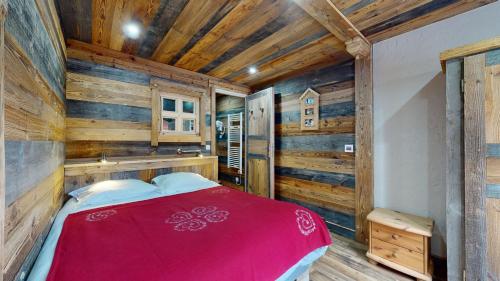 - une chambre avec un lit rouge dans une pièce dotée de murs en bois dans l'établissement Résidence Hôtelière Bellecôte 4 étoiles, à La Plagne Tarentaise