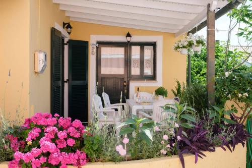 un patio con sedie bianche e fiori di fronte a una casa di Zervou House North Corfu a Loútsai