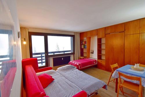 sala de estar con muebles de color rojo y mesa en Carlo Magno Studio apartment en Madonna di Campiglio