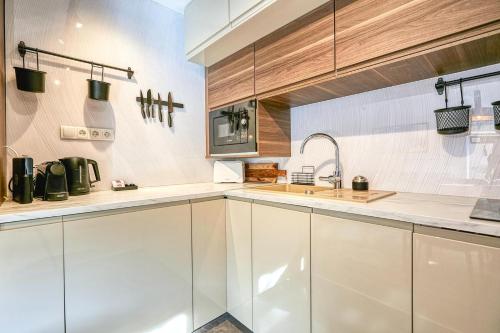 a kitchen with white cabinets and a sink at Villa Botaniq in Sopron