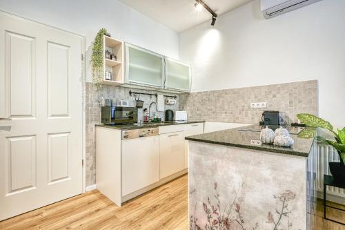 a kitchen with white cabinets and a counter top at Villa Botaniq in Sopron