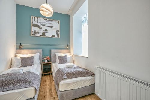 two beds in a room with blue walls at Villa Botaniq in Sopron