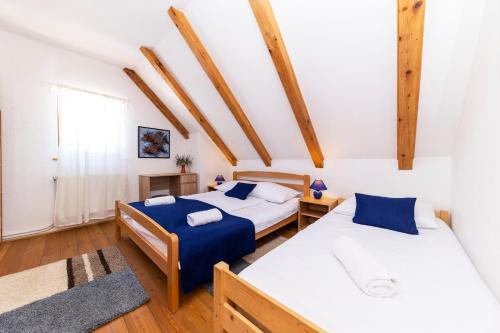 Duas camas num quarto com vigas de madeira em SPA HOLIDAY HOUSE REŽEK - Lovinac em Lovinac