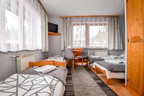 a room with three beds and a table and chairs at U Cudzicha in Zakopane