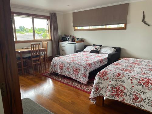 a bedroom with two beds and a kitchen with a table at Haven on Glenaven B&B in Motueka