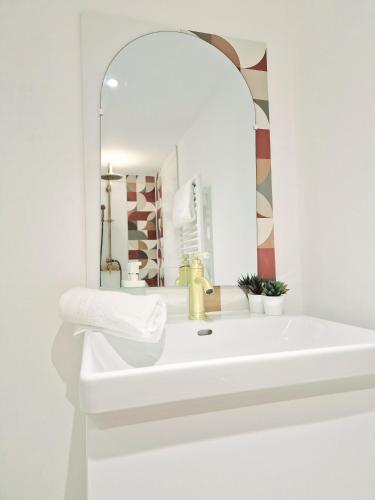 une salle de bain blanche avec un lavabo et un miroir dans l'établissement L'élémentaire, appartement chic et central, à Mulhouse