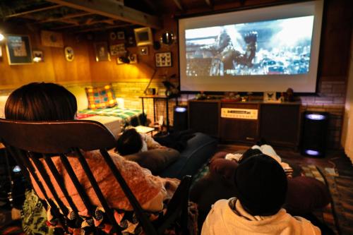 a group of people sitting in chairs watching a television at MOSAIC hinohara in Motojuku