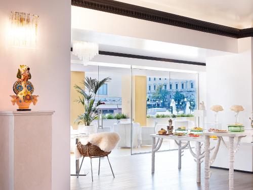 a white dining room with a white table and chairs at Grecotel Pallas Athena in Athens