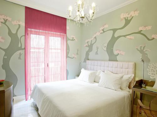 a bedroom with a white bed and a tree mural at Grecotel Pallas Athena in Athens