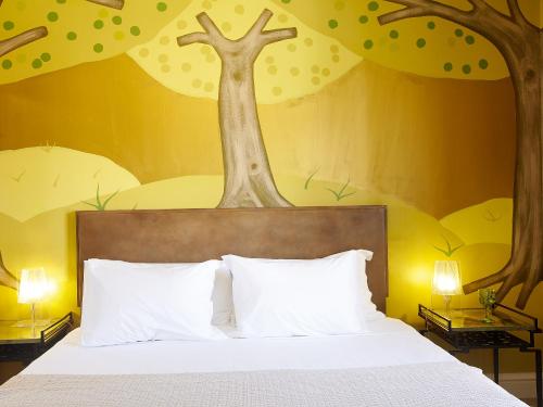 a bedroom with a bed with a tree mural on the wall at Grecotel Pallas Athena in Athens