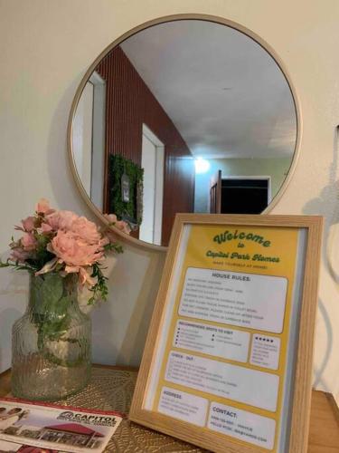 a sign on a table with a mirror and a vase with flowers at 2B Tiny Home in Iba Zambales in Iba