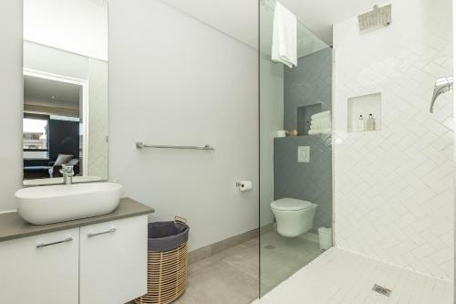 a white bathroom with a sink and a toilet at Chic Urban Oasis with character in Cape Town