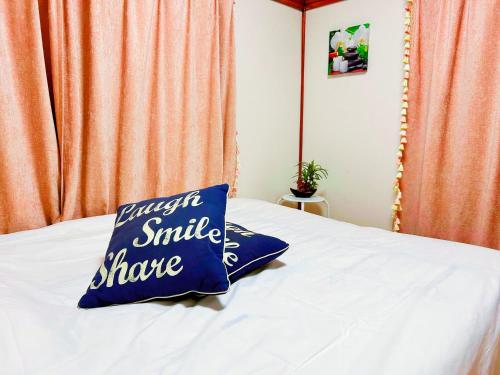a pillow on a bed with a smile share sign on it at yikebukuro LuckyHouse 池袋一軒家 幸運の家 in Tokyo