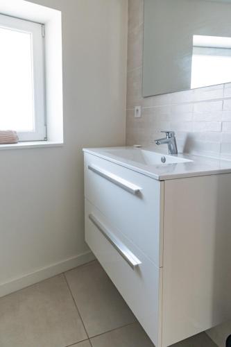 une salle de bain blanche avec un lavabo et un miroir dans l'établissement Make My Day, Champagne au Mont d'or, à Champagne-au-Mont-dʼOr