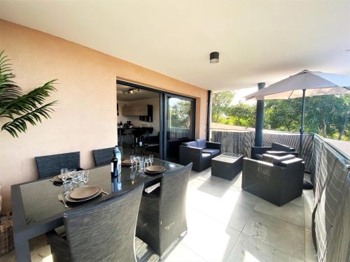 un restaurant avec des tables, des chaises et un parasol dans l'établissement Les terrasses de l'Isolella, à Porticcio
