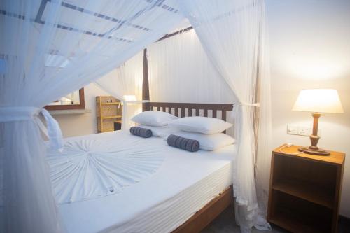 ウナワトゥナにあるTHE CHILLI STUDIO APARTMENTの白い枕と天蓋付きの白いベッド