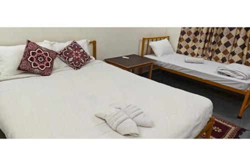 1 dormitorio con 2 camas con almohadas y mesa en Rococo Pelton beach huts Palolem Beach goa, en Palolem