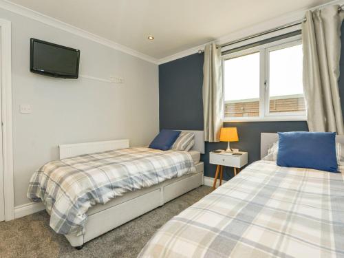 a bedroom with two beds and a tv on the wall at Lilys Pad in Okehampton