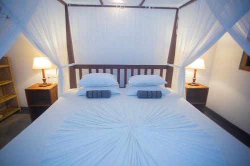 a bedroom with a large white bed with two lamps at THE CHILLI STUDIO APARTMENT in Unawatuna