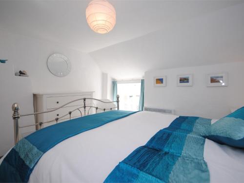 a white bedroom with a large bed with blue sheets at 1 Bed in Burton Bradstock DC016 in Burton Bradstock