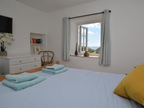 um quarto com uma cama com almofadas azuis e uma janela em 2 Bed in Charmouth DC077 em Charmouth