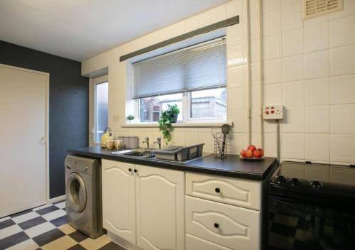 a kitchen with a sink and a washing machine at Charming Family Apartment - Stay Longer, Save More! in Lincolnshire