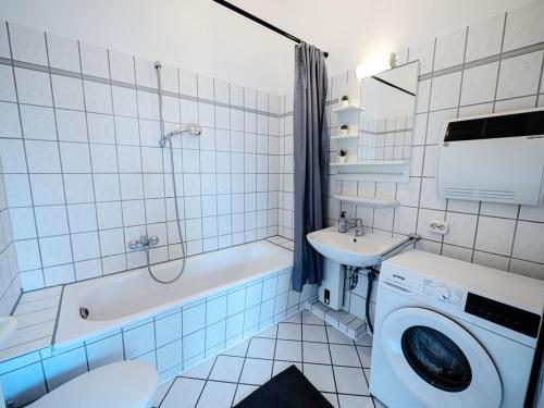 a bathroom with a tub sink and a washing machine at Work & Stay in Ahrensburg bei Hamburg in Ahrensburg