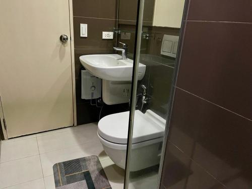 a bathroom with a toilet and a sink at Homey 1BR Acqua Livingstone with Netflix, Pool & Gym in Manila