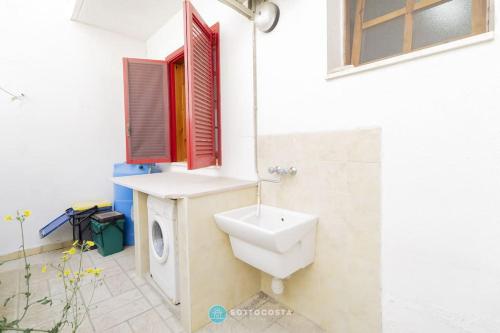 a bathroom with a toilet and a sink and a window at Orsetta Flat - Torre Dell'Orso in Torre dell'Orso