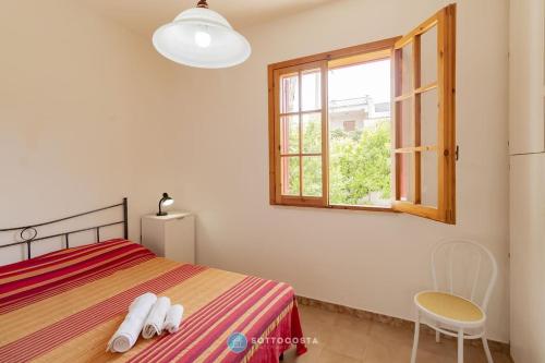 a bedroom with a bed and a window and a chair at Orsetta Flat - Torre Dell'Orso in Torre dell'Orso