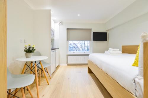 1 dormitorio con cama, mesa y ventana en Queensborough Terrace Serviced Apartments by Concept Apartments en Londres