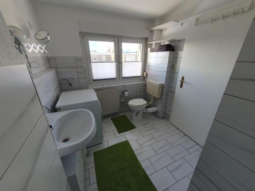 een witte badkamer met een wastafel en een toilet bij Neumühler Hof- Ferienwohnung "Thomas" 3 Zimmer,3 Bäder mit Dusche, kostenfreie Parkplätze vor dem Haus in Schwerin