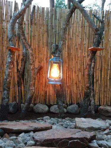 a lantern hanging between two trees in front of a fence at Queen Elizabeth Bush Lodge by NATURE LODGES LTD in Bushenyi